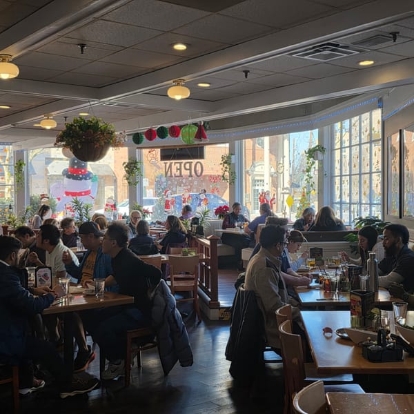 A busy Sala Thai dining room with patrons seated at tables and large windows decorated for holidays.