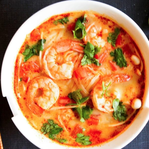 Close-up of a white bowl filled with Sala Thai's Tom Yum soup, featuring shrimp, noodles, and cilantro.