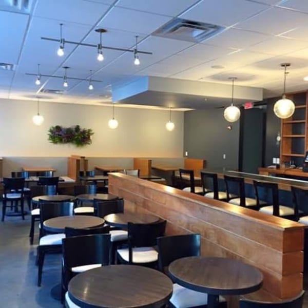 Interior of Sala Thai restaurant with empty tables, chairs, and a bar area with pendant lighting.