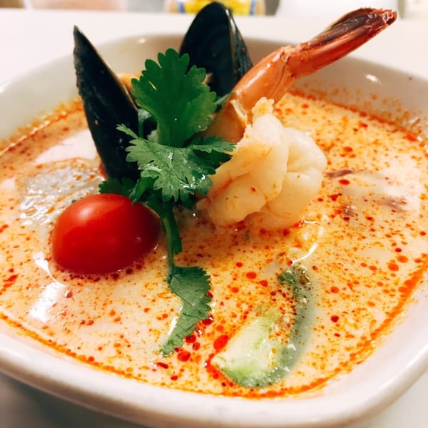Sala Thai's Tom Yum soup with shrimp, mussels, cherry tomato, and cilantro in a white bowl.