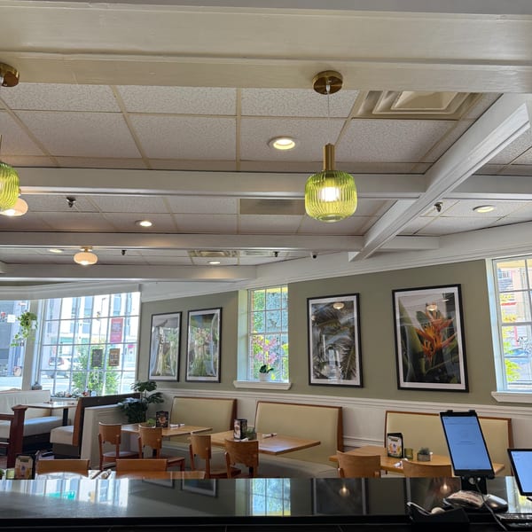 Interior of Sala Thai restaurant with light green walls, framed botanical art, and booth seating.