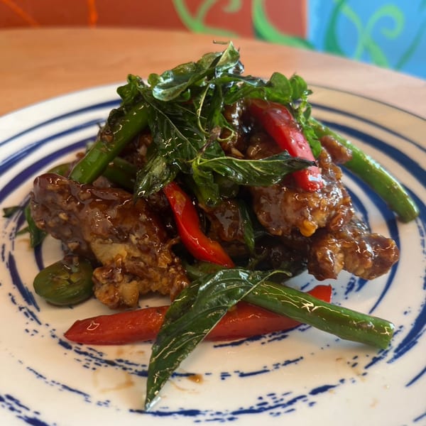 Sala Thai's crispy pork with basil, green beans, and red peppers on a white and blue plate.