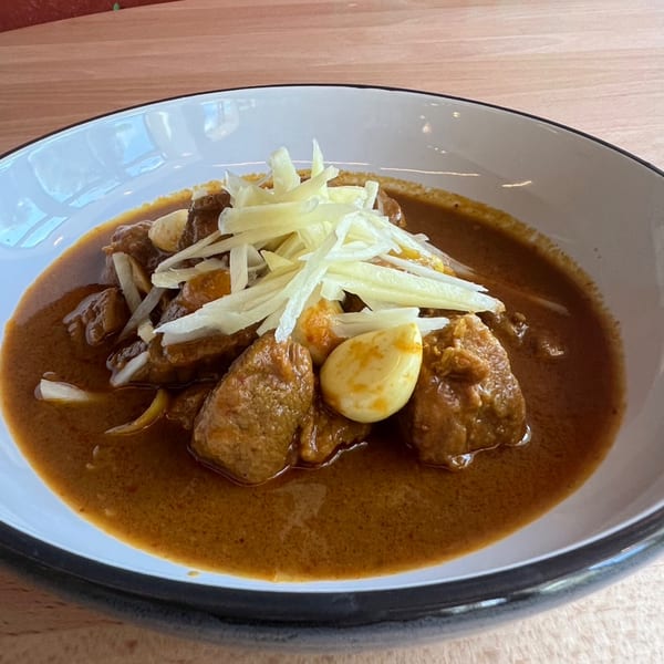 Close-up of Sala Thai's Massaman Curry with tender beef, whole garlic cloves, and shredded ginger.