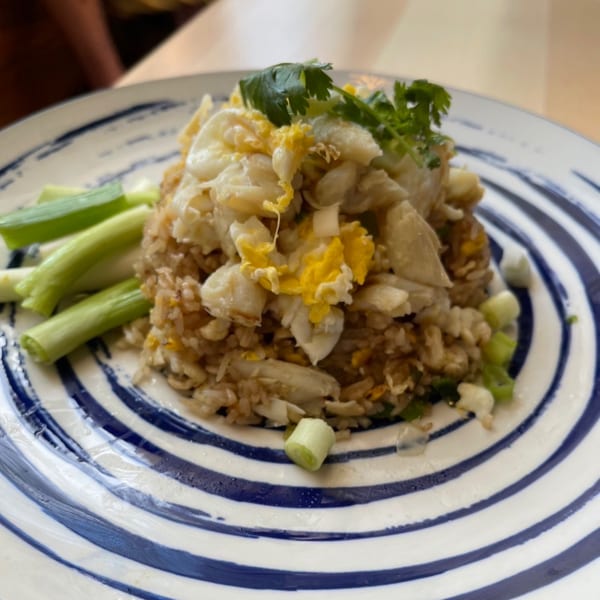 Sala Thai's crab fried rice, topped with cilantro and served with green onions on a striped plate.