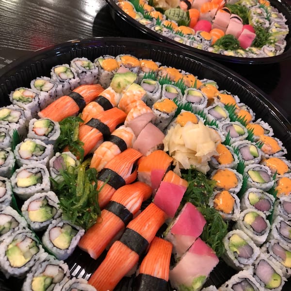 Two large platters overflowing with various colorful sushi rolls, nigiri, and sashimi from Sala Thai.