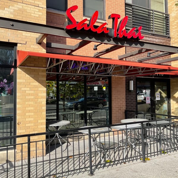The Sala Thai restaurant exterior with a red awning, outdoor seating, and brick facade.