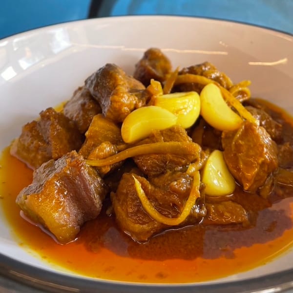 Close-up of Sala Thai's Massaman Curry with tender beef, whole garlic cloves, and ginger in a rich sauce.