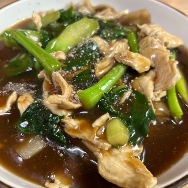 Close-up of Sala Thai's chicken and green vegetables in a rich brown sauce, sprinkled with pepper.