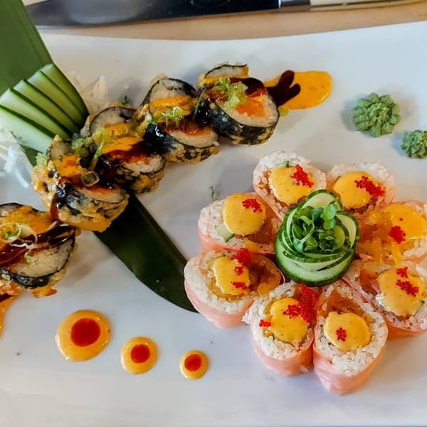 A plate of Sala Thai sushi rolls, including fried rolls and flower-shaped rolls with sauce and roe.