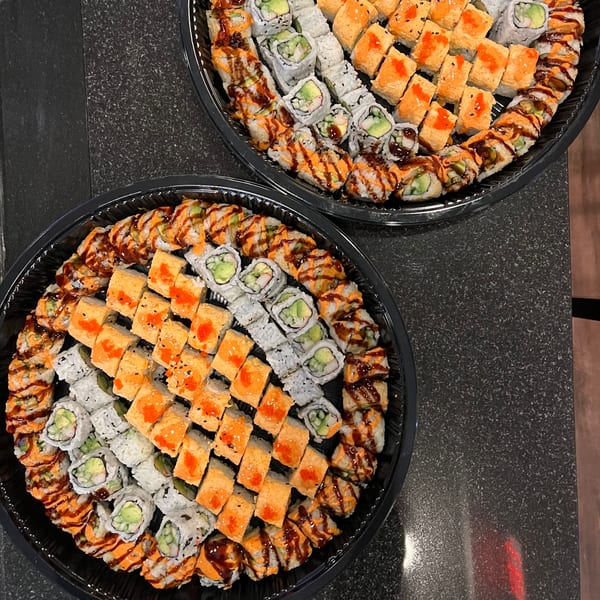 Two large platters of assorted Sala Thai sushi rolls, including avocado, spicy tuna, and salmon roe.