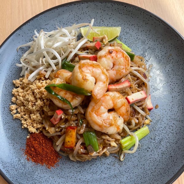 Sala Thai's Pad See Ew with shrimp, bean sprouts, lime, and chili flakes on a speckled plate.